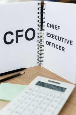 notebook with cfo and chief executive officer lettering near calculator and pencils clipart