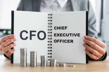 stacked silver coins near woman holding notebook with cfo and chief executive officer lettering  clipart