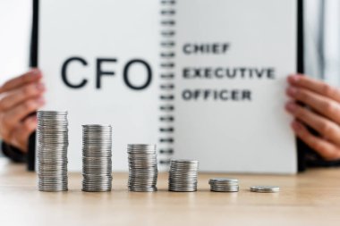 stacked silver coins near blurred tax inspector holding notebook with cfo and chief executive officer lettering  clipart