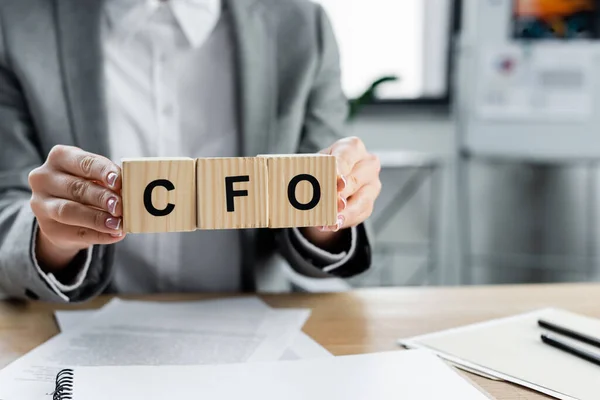 Cfoの文字で木製の立方体を保持している実業家のクロップドビューオフィスで — ストック写真