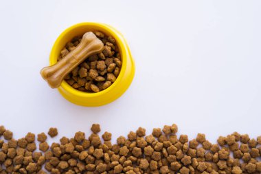 Sarı plastik kasenin üst görüntüsü, evcil hayvan maması ve köpek maması beyaza izole edilmiş.