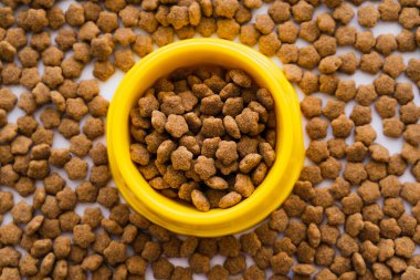 top view of dry pet food in plastic yellow bowl  clipart