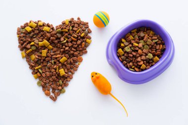 Kase yakınındaki kuru evcil hayvan mamasından yapılmış kalp manzarası ve beyaz tenli plastik oyuncaklar.
