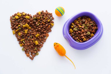 top view of heart made of dry pet food near bowl and rubber toys isolated on white clipart