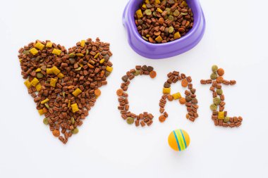 Kalp ve kedi kelimesinin üst görüntüsü kuru hayvan mamasından yapılmıştır. Kasenin yanında ve top beyazda izole edilmiştir.