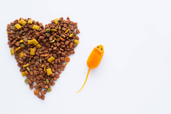 top view of dry cat food in shape of heart near near rubber toy mouse isolated on white