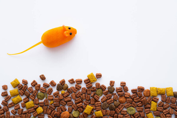 top view of rubber toy near cat dry food on white background