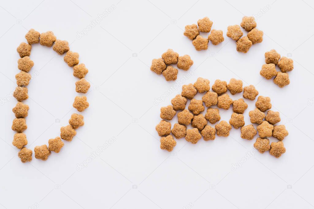 Top view of paw shape made of dry pet food near letter isolated on white