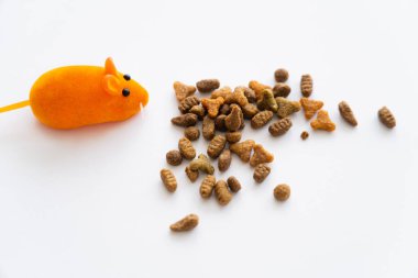 top view of dry cat food near orange rubber mouse isolated on white clipart