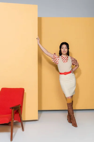 Ασιατικό Μοντέλο Ρετρό Ρούχα Που Ποζάρουν Κοντά Πολυθρόνα Πορτοκαλί Φόντο — Φωτογραφία Αρχείου