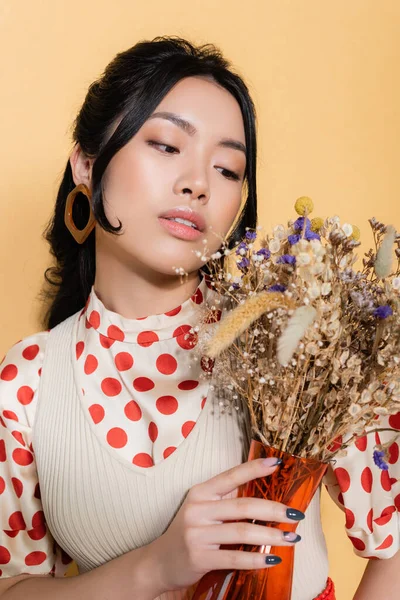 穿着复古服装的时髦的亚洲女人的画像 看着用橙子隔开的花朵 — 图库照片