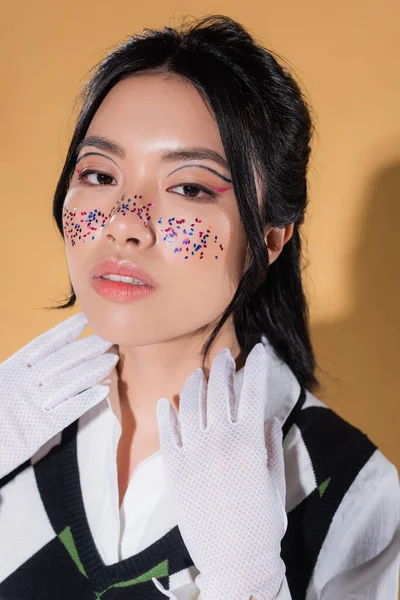 Μοντέρνο Ασιατικό Μοντέλο Glitter Στο Πρόσωπο Κοιτάζοντας Κάμερα Πορτοκαλί Φόντο — Φωτογραφία Αρχείου
