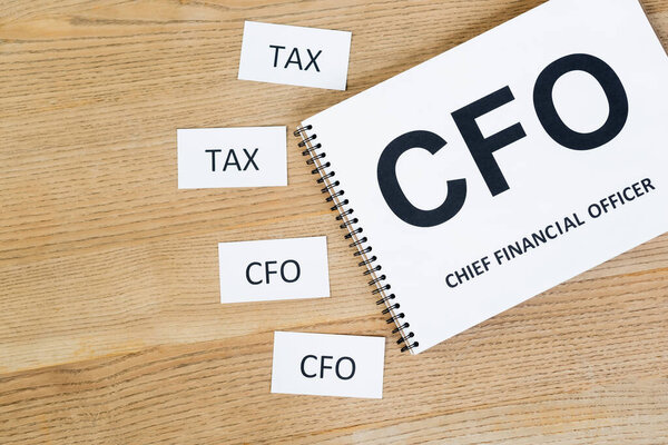 top view of notebook with cfo and chief financial officer lettering near papers with abbreviation on desk