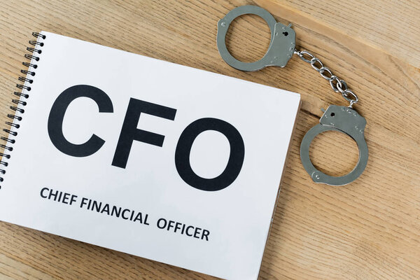 top view of notebook with cfo lettering near handcuffs on desk