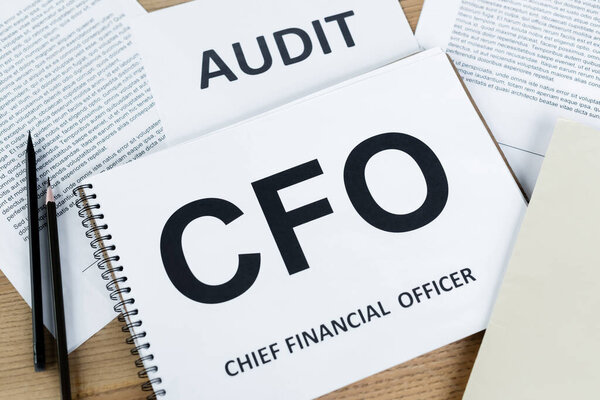 top view of notebook with cfo abbreviation near paper with audit lettering on desk