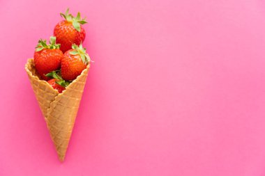 Pembe arka planda waffle külahında taze çilek manzarası 