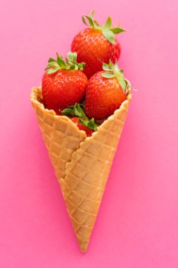 Pembe arka planda waffle külahında sulu çileklerin üst görüntüsü 