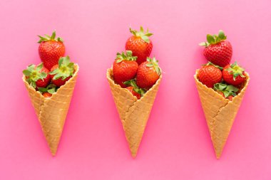 Pembe arka planda çilekli waffle külahları vardı. 