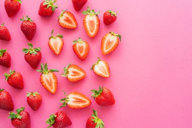 Düz yatıyordu, kırmızı kesim ve pembe arka planda tüm çilekler 