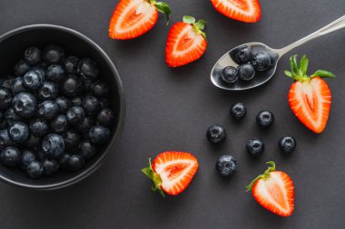 Kaşık yakınındaki taze böğürtlen manzarası ve siyah arka planda kase 