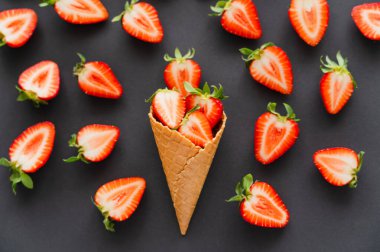 Flat lay with cut strawberries in waffle cone on black background  clipart