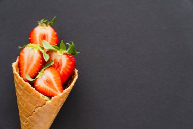 Siyah yüzeyde waffle külahında sulu çileklerin üst görüntüsü