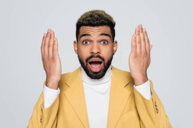 Afrika kökenli, balıkçı yakalı, sarı renkli spor ceketli, griye bürünmüş Amerikalı bir adam. 