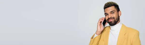穿着黄色夹克的快乐的非洲裔美国人 在灰色横幅上用智能手机交谈 — 图库照片