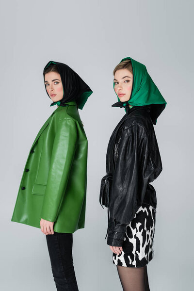 женщин в модных кожаных куртках и платках, смотрящих в камеру, изолированную на сером