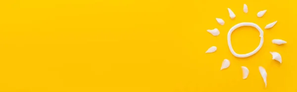 黄色の背景に日焼け止めクリームからの白い太陽のサインのトップビュー バナー — ストック写真