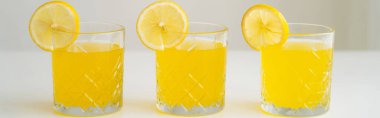 glasses with refreshing lemonade with slices of juicy lemon on white surface isolated on grey, banner clipart