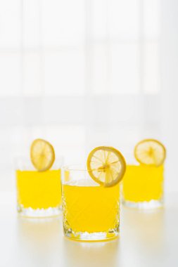 Ferahlatıcı limon toniği ve beyaz arka planda limon dilimleri olan fotokopi alanı olan bardaklar.