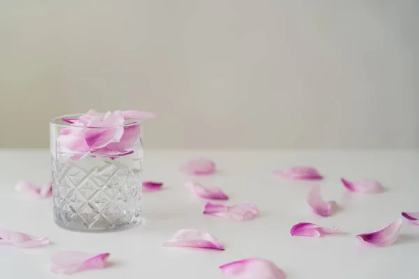 Facettiertes Glas Gin Tonic Mit Blütenblättern Auf Weißer Oberfläche Isoliert — Stockfoto