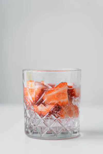 灰色に隔離された白い表面に新鮮なイチゴの強壮剤とガラスのクローズアップ — ストック写真