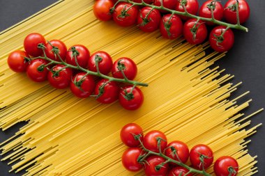 Siyah arka planda çiğ spagettide kiraz domateslerinin üst görüntüsü. 