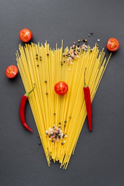 Kırmızı sebzeler ve siyah arka planda spagetti üzerine baharatlarla yatıyordu. 