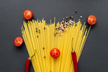 Siyah arka planda çiğ spagetti üzerine baharat ve kırmızı biber. 