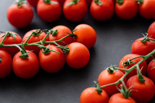 Close up view of fresh cherry tomatoes on branches on black background 