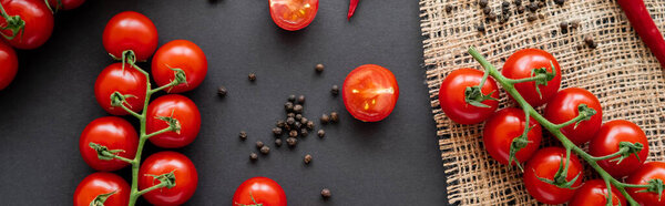 Top view of ripe vegetables and peppercorns on sackcloth on black background, banner 
