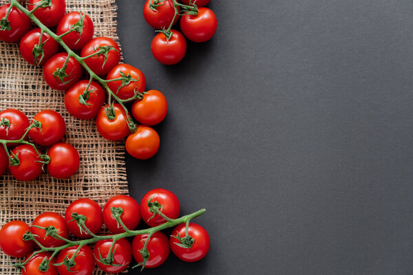 Top view of fresh cherry tomatoes on sackcloth on black background 