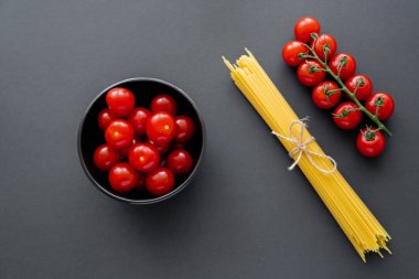 Siyah yüzeyde kiraz domatesleri ve pişmemiş makarna manzarası 