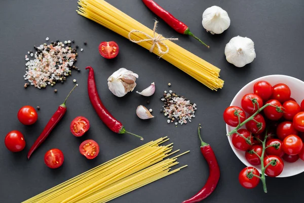 Siyah yüzeydeki baharatların yanında doğal sebze ve makarna manzarası. 