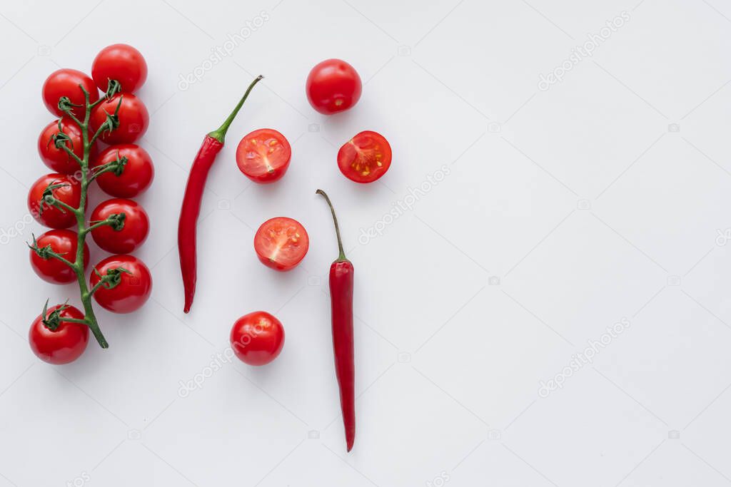 Top view of ripe chili peppers and cherry tomatoes on white background 