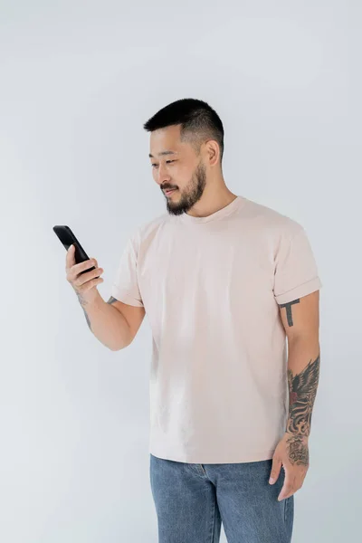 Smiling Asian Man Tattoos Using Smartphone Isolated Grey — Stock Photo, Image