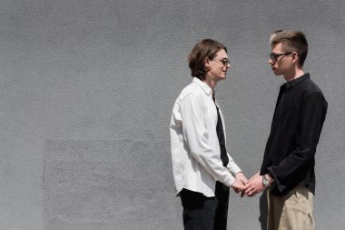 Eşcinsel bir çiftin bina yakınlarında el ele tutuşması. 