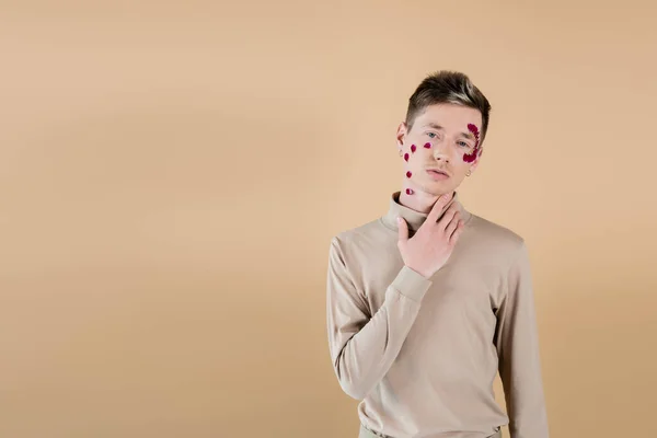 Man Met Bloemblaadjes Gezicht Kijkend Naar Camera Geïsoleerd Beige — Stockfoto