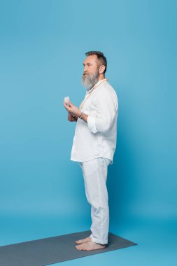 Mavi arkaplanda selenit taşıyla meditasyon yapan yalınayak guru akıl hocası.