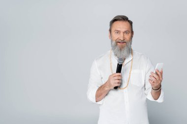 Motivasyon gurusu ve cep telefonu ile mikrofonla konuşan gri üzerinde izole edilmiş.