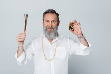 Gri renkli kameraya gülümseyen aroma çubukları ve kokulu yağlı ayurveda gurusu.