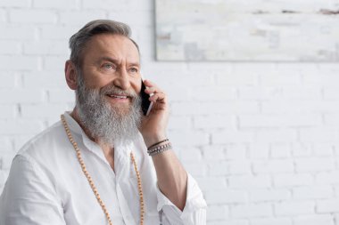 Evde akıllı telefondan konuşan boncuklu usta guru.